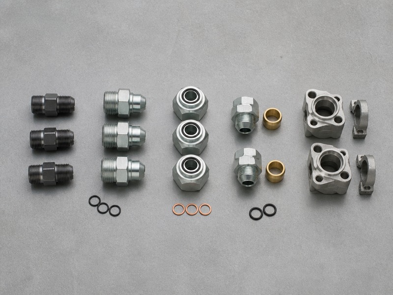 Thirteen hydraulic fittings arranged by thread family, including NPT and JIC 37 degree flare, ORFS, SAE ORB O-ring boss, BSPP and BSPT parallel and tapered pipe threads, metric 24 degree cone, JIS 30 degree flare, SAE Code 61 and Code 62 flange, banjo and hose end fittings