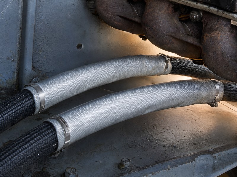 Silicone-coated fibreglass heat sleeve fitted over hydraulic hose runs passing close to an exhaust manifold with a standoff air gap